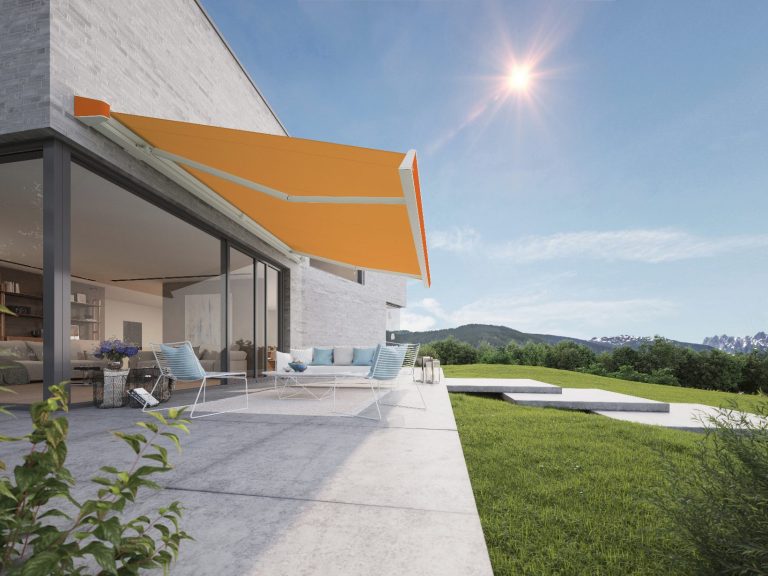 Moderne Terrasse mit oranger Markise und Blick auf eine grüne Landschaft.